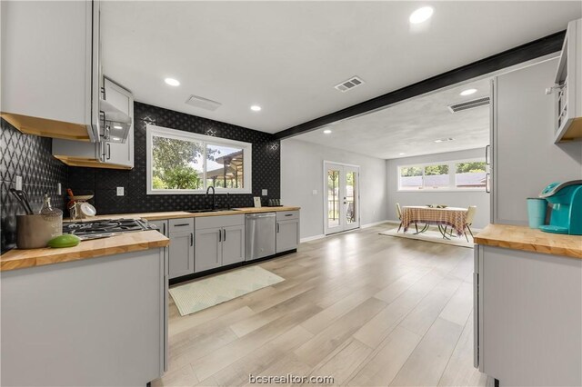 kitchen featuring sink, dishwasher, french doors, butcher block countertops, and light wood-type flooring