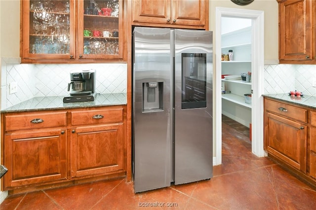 kitchen featuring dark stone countertops, stainless steel fridge with ice dispenser, backsplash, and dark tile patterned flooring