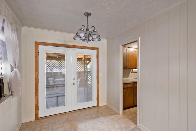 interior space featuring french doors, a textured ceiling, an inviting chandelier, and a wealth of natural light