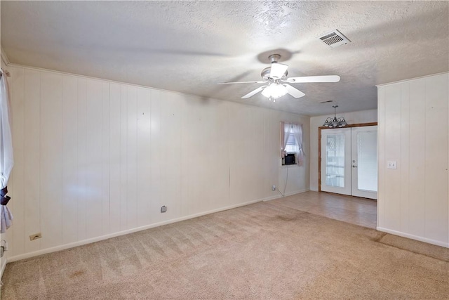 empty room featuring light colored carpet, a textured ceiling, and french doors