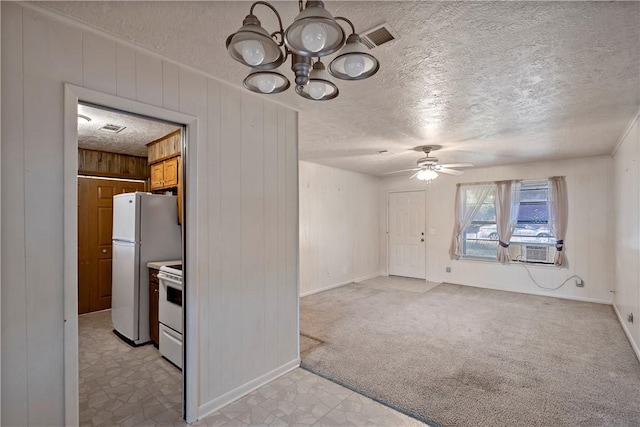 interior space with ceiling fan with notable chandelier, light colored carpet, a textured ceiling, and wooden walls