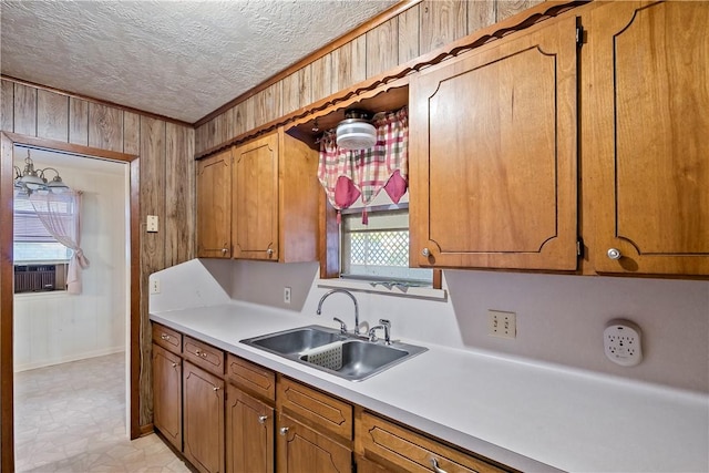 kitchen with a textured ceiling, wood walls, and sink