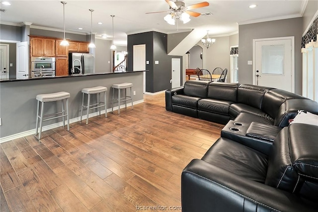 living room featuring ceiling fan with notable chandelier, light hardwood / wood-style flooring, and ornamental molding