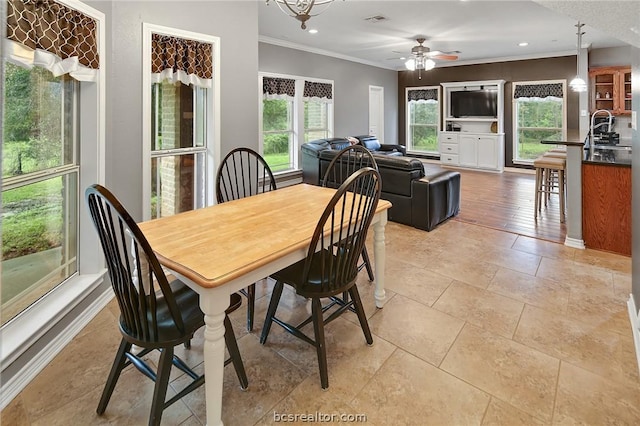 dining area featuring ceiling fan with notable chandelier, ornamental molding, and sink