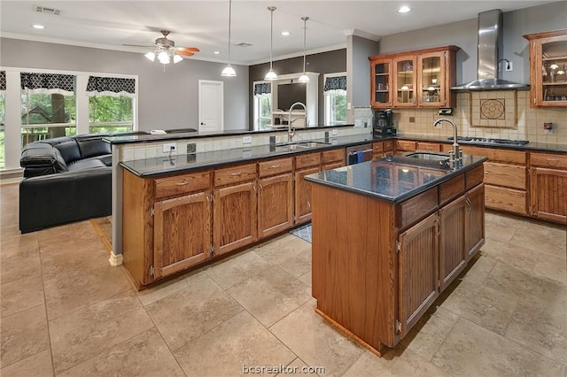 kitchen with sink, wall chimney range hood, kitchen peninsula, and a wealth of natural light