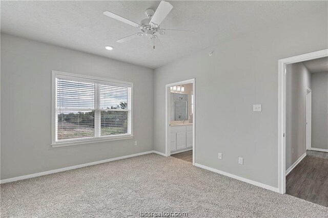 empty room featuring ceiling fan and dark colored carpet