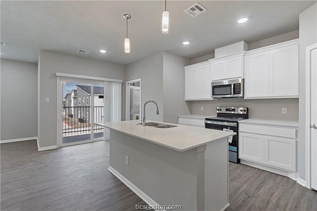 kitchen featuring white cabinetry, sink, hanging light fixtures, stainless steel appliances, and a center island with sink