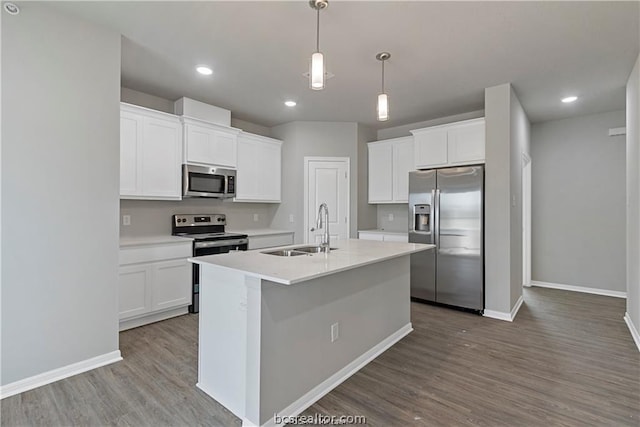 kitchen with pendant lighting, a center island with sink, sink, appliances with stainless steel finishes, and white cabinetry