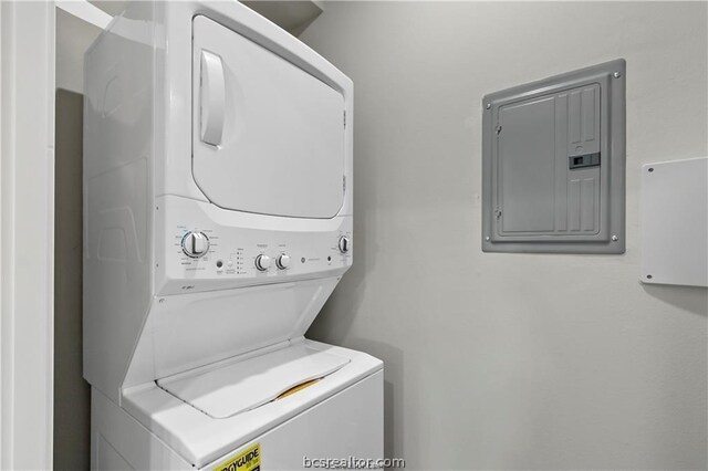 laundry area with stacked washer / drying machine and electric panel