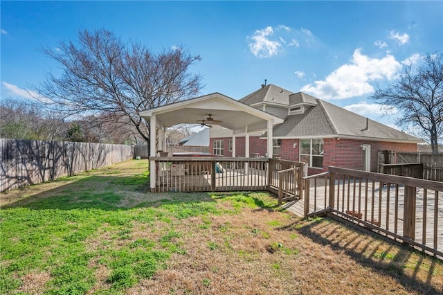 view of front of house featuring a wooden deck, ceiling fan, and a front lawn