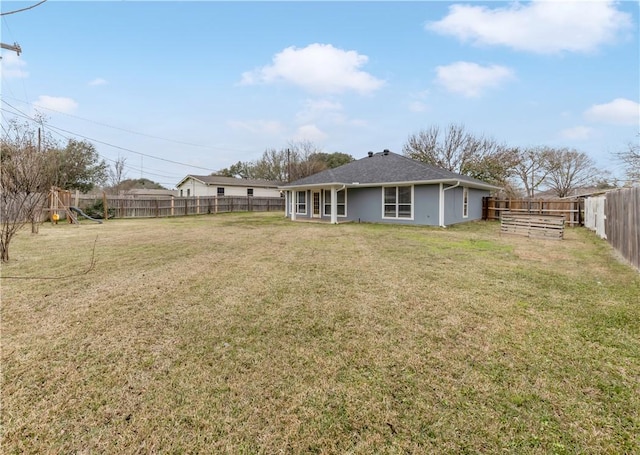 back of house featuring a yard and a playground