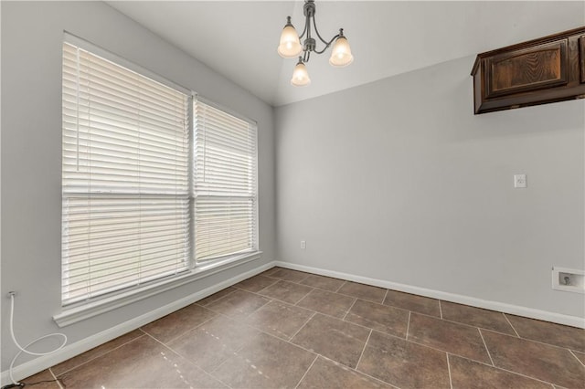 empty room with a notable chandelier and tile patterned floors