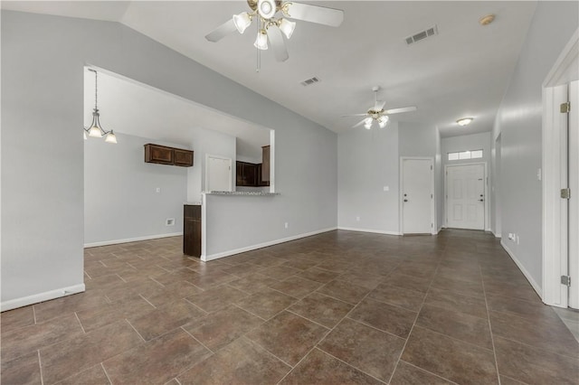 unfurnished living room with ceiling fan, vaulted ceiling, and dark tile patterned floors