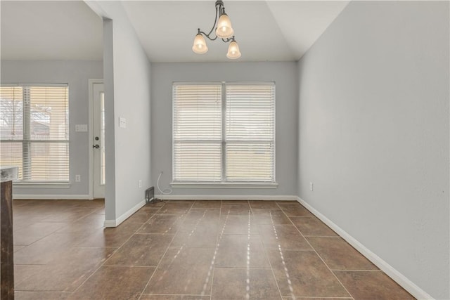 interior space with an inviting chandelier, dark tile patterned flooring, and vaulted ceiling