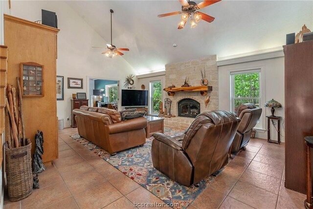 living room featuring a stone fireplace, a wealth of natural light, high vaulted ceiling, and light tile patterned floors