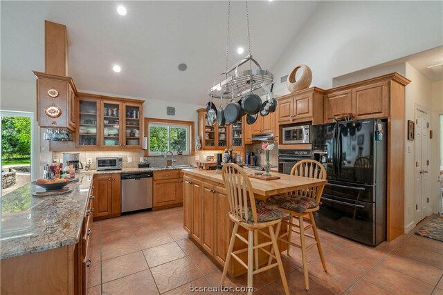 kitchen with a kitchen island, butcher block countertops, sink, decorative backsplash, and black appliances