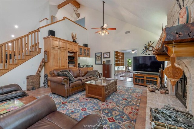 tiled living room with ceiling fan, a stone fireplace, and high vaulted ceiling