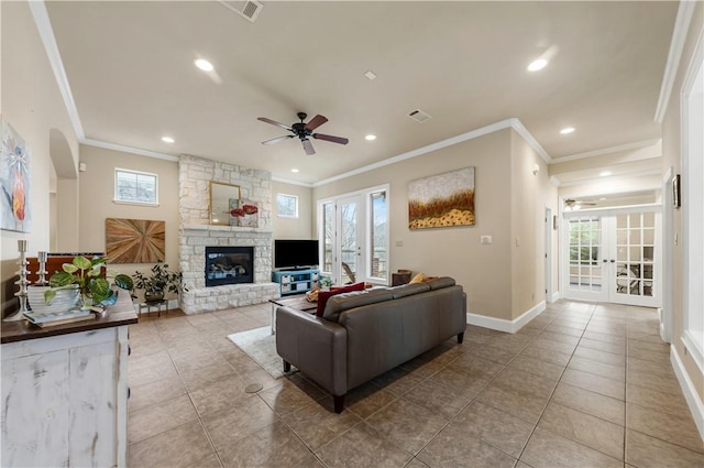 tiled living room featuring ornamental molding, a stone fireplace, plenty of natural light, and french doors