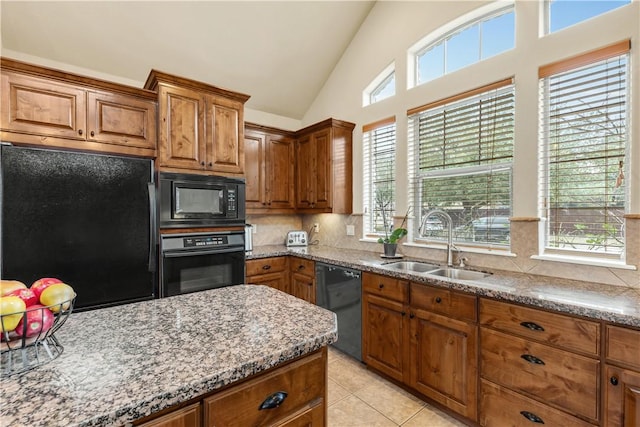 kitchen featuring lofted ceiling, sink, light tile patterned floors, tasteful backsplash, and black appliances