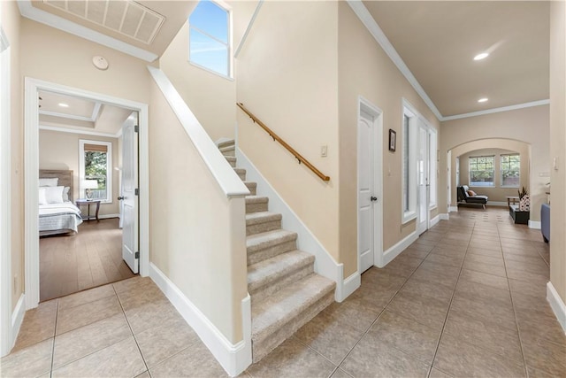 corridor with crown molding, a healthy amount of sunlight, and light tile patterned flooring