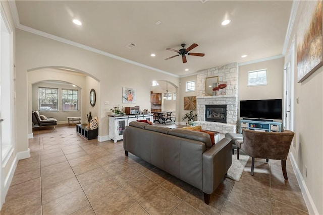 living room featuring tile patterned flooring, ornamental molding, a fireplace, and ceiling fan