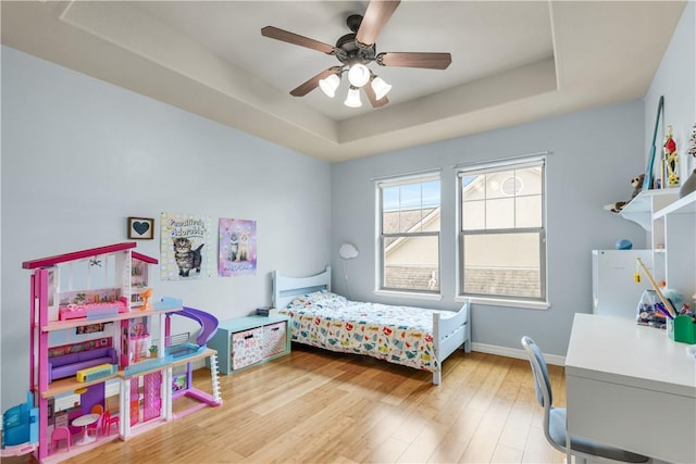 bedroom featuring hardwood / wood-style floors, a tray ceiling, and ceiling fan