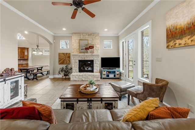 tiled living room featuring ceiling fan with notable chandelier, a fireplace, ornamental molding, and beverage cooler