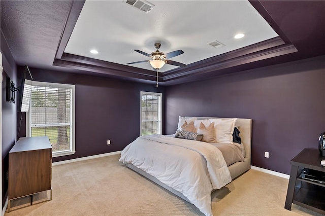 bedroom with a tray ceiling, multiple windows, ceiling fan, and light colored carpet