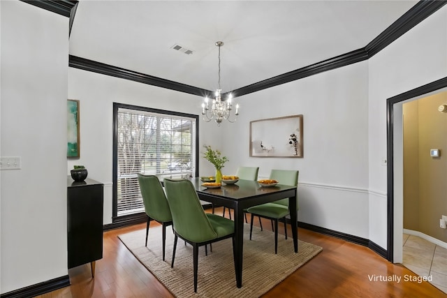 dining room featuring hardwood / wood-style floors, a notable chandelier, and crown molding