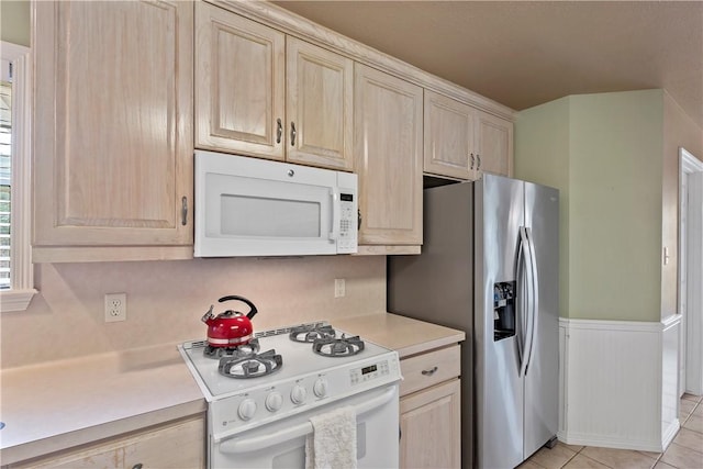 kitchen with light tile patterned floors, white appliances, and light brown cabinetry