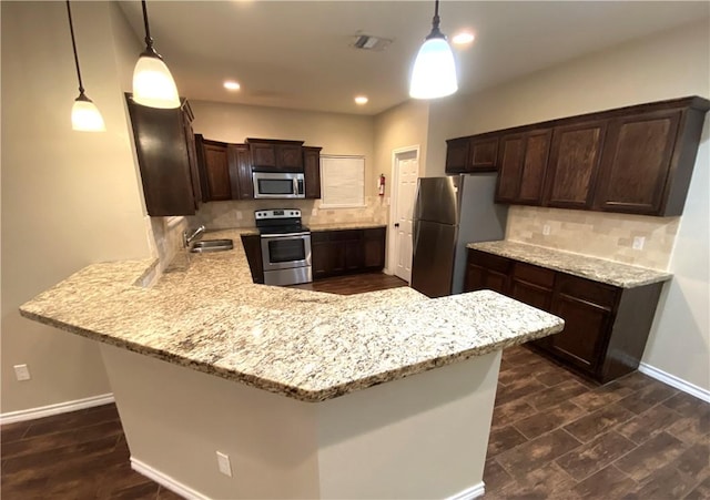 kitchen with a peninsula, dark brown cabinets, appliances with stainless steel finishes, and decorative backsplash
