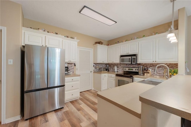 1610 Ethic Ln, College Station, TX 77845 - kitchen with appliances with stainless steel finishes, a sink, backsplash, light wood-style flooring, and white cabinetry