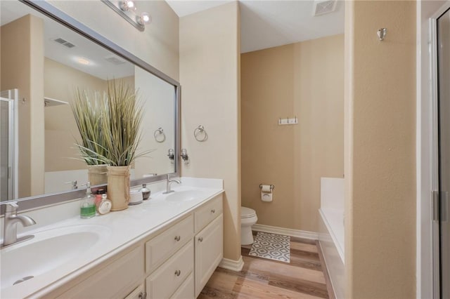 1610 Ethic Ln, College Station, TX 77845 - bathroom featuring toilet, an enclosed shower, double vanity, wood finished floors, and a tub to relax in