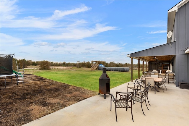 view of patio / terrace with outdoor dining space, a trampoline, a playground, and a ceiling fan