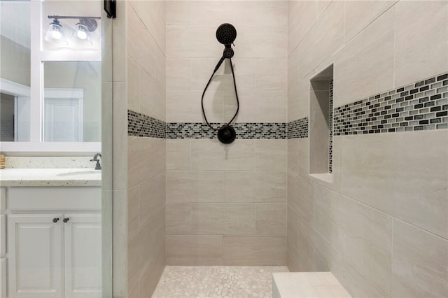 full bathroom featuring a tile shower and vanity