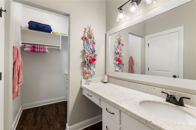 bathroom featuring wood finished floors, vanity, and baseboards