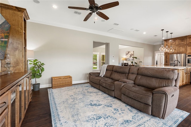 living area with ceiling fan, visible vents, baseboards, ornamental molding, and dark wood finished floors