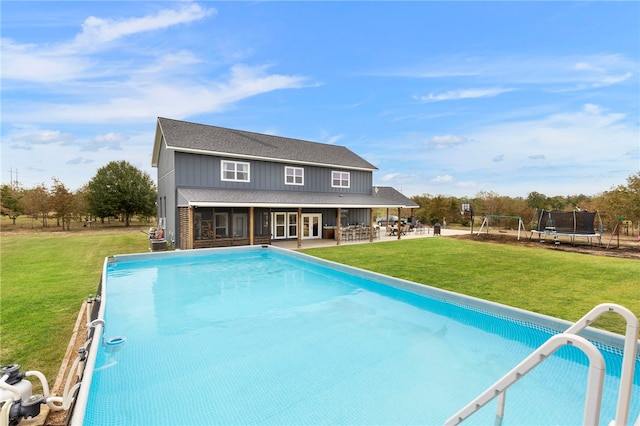 outdoor pool featuring a trampoline, a patio area, and a lawn