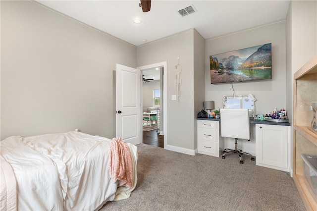 bedroom featuring visible vents, a ceiling fan, light carpet, built in study area, and baseboards