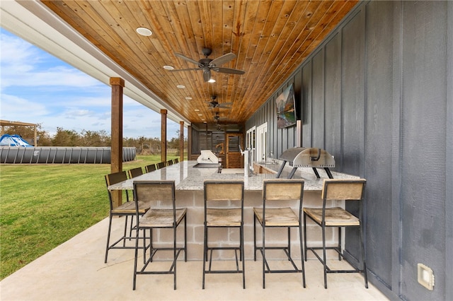 view of patio featuring a ceiling fan, outdoor wet bar, and an outdoor kitchen