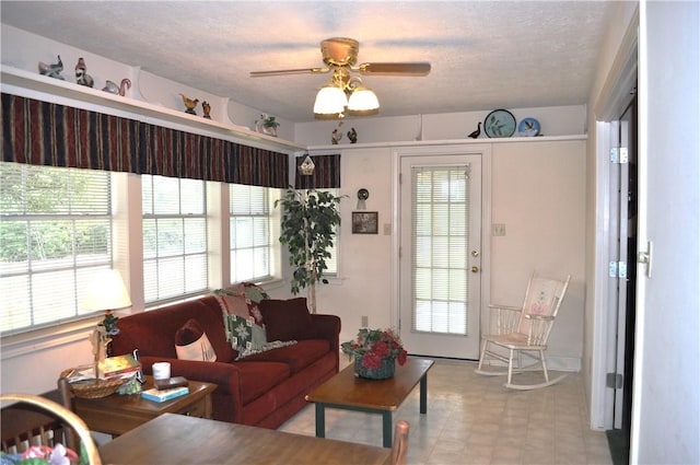 living room with ceiling fan, a textured ceiling, and a wealth of natural light