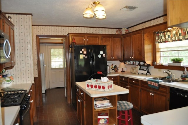 kitchen featuring a center island, crown molding, black appliances, and sink