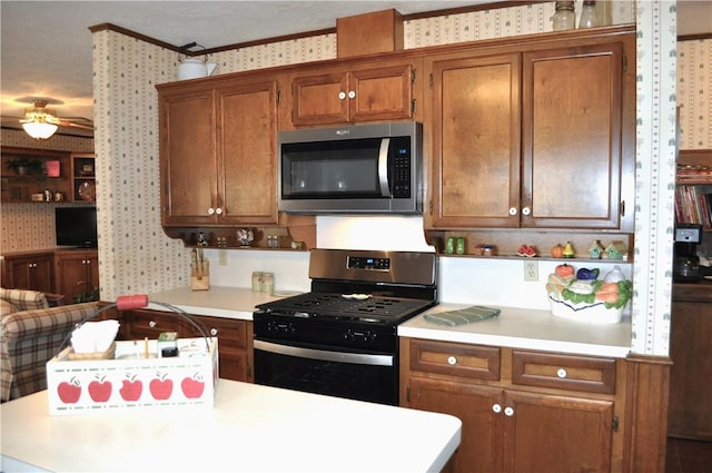 kitchen with ceiling fan, crown molding, and stainless steel appliances