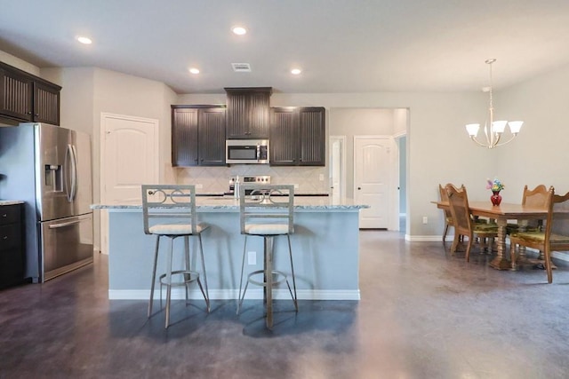 12029 Eagle Ln, North Zulch, TX 77872 - kitchen featuring appliances with stainless steel finishes, decorative backsplash, concrete flooring, a kitchen bar, and dark brown cabinets