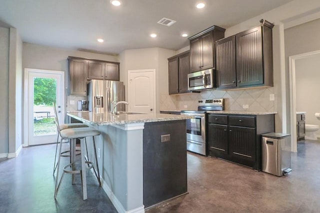 12029 Eagle Ln, North Zulch, TX 77872 - kitchen with stainless steel appliances, finished concrete floors, backsplash, a center island with sink, and recessed lighting