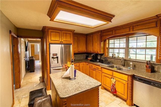 kitchen featuring light stone countertops, sink, a center island, a textured ceiling, and appliances with stainless steel finishes