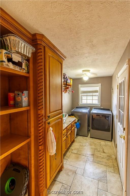 laundry room with cabinets, a textured ceiling, and washing machine and dryer