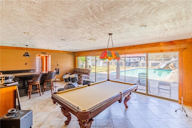 game room with ornamental molding, a textured ceiling, light tile patterned floors, billiards, and bar area