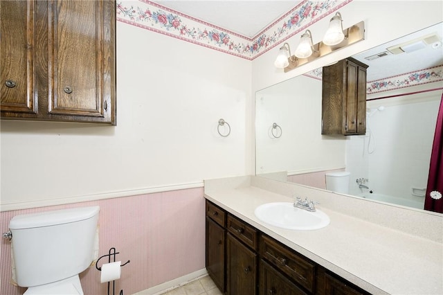 bathroom featuring shower / bath combination, wainscoting, vanity, and toilet