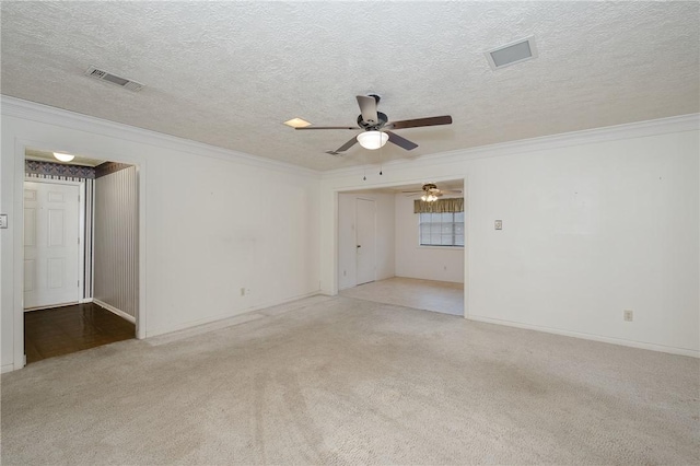 empty room featuring crown molding, visible vents, and light colored carpet